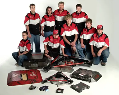 A group of people posing for a picture with some electronics.
