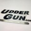 A sticker that says udder gun. Com with a ruler